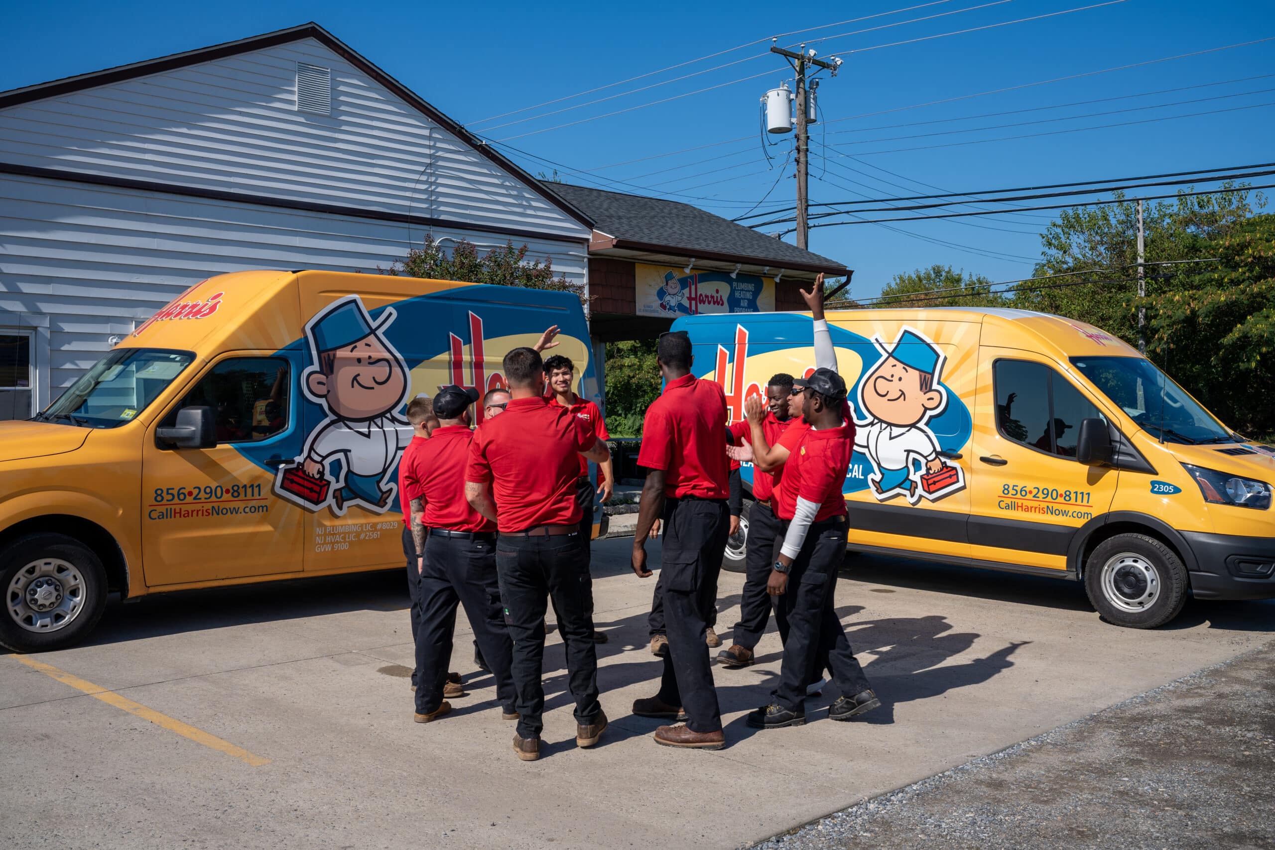 A team of Harris employees gather between two company vans.