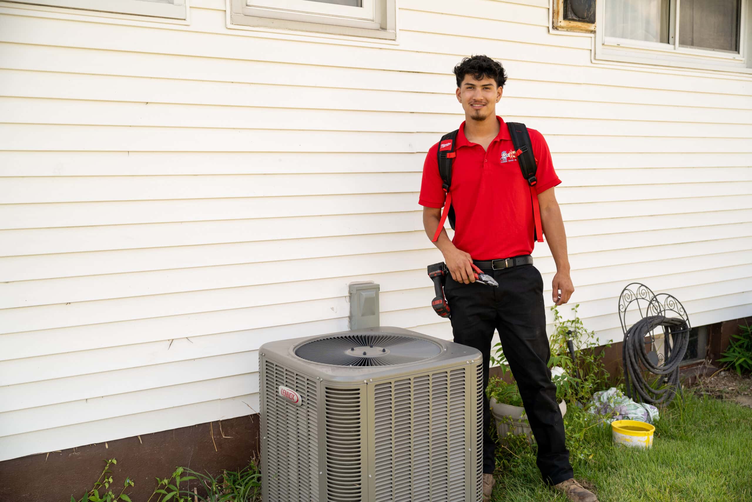 A Harris employee stands beside an HVAC system.