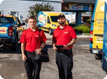 Two Harris employees pose in front of three company vehicles.